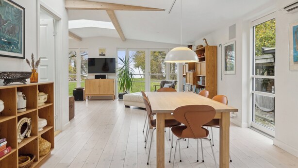 Une cuisine moderne avec un coin repas, des meubles en bois, un téléviseur et une grande fenêtre.