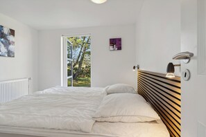 Ein Schlafzimmer mit einem Bett, einem Fenster und einer Wandleuchte.