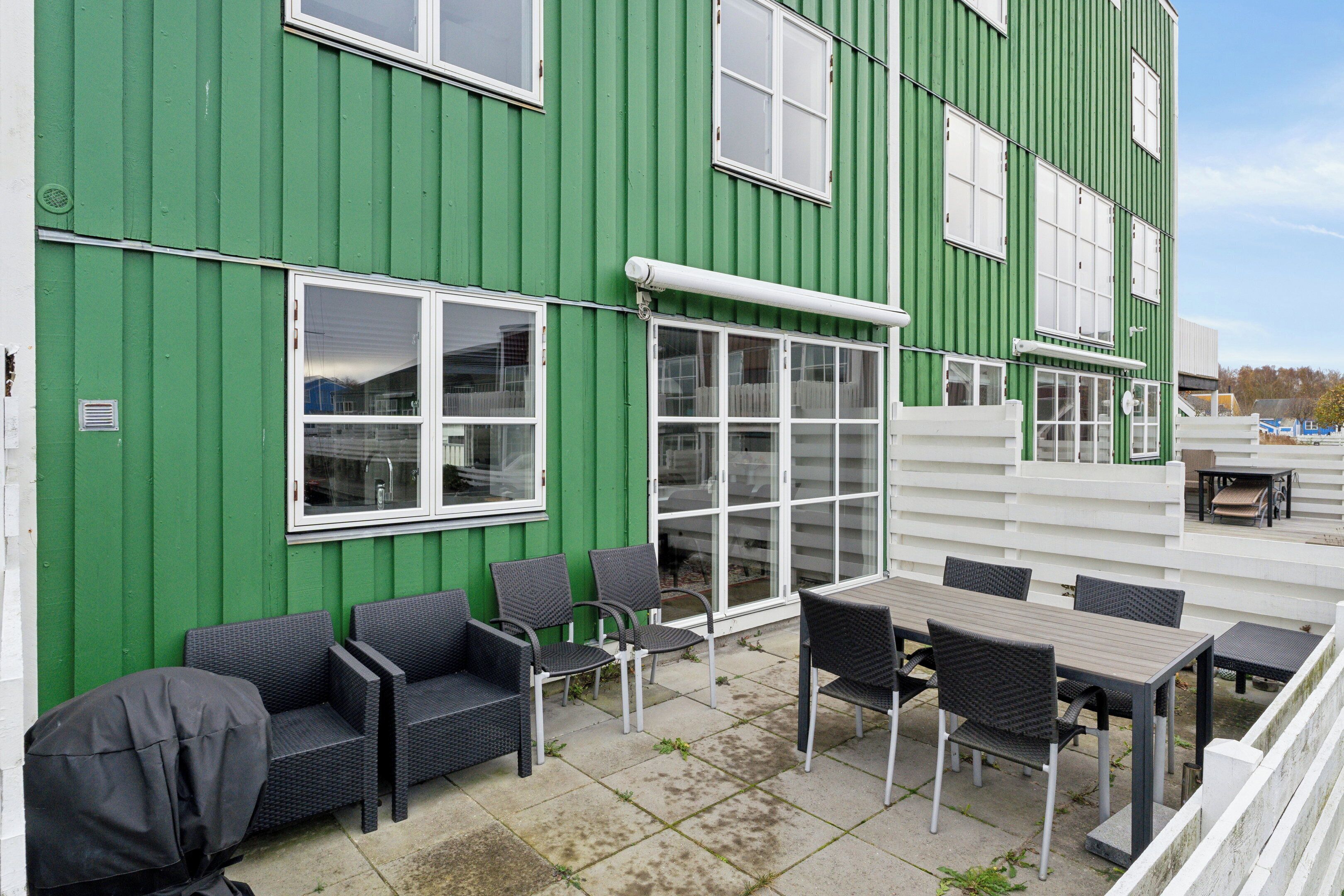 Un edificio verde con un patio que incluye mobiliario exterior y una mesa.