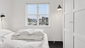 Une pièce avec un lit, une fenêtre et deux lampadaires.