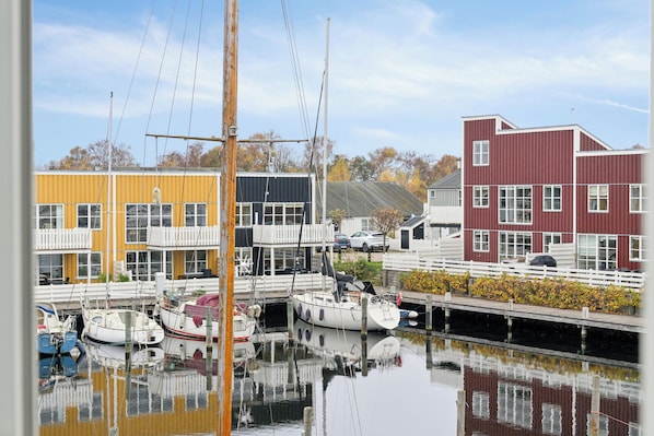 Een jachthaven met aangemeerde boten, een wit hek en gebouwen met gele en rode gevels.
