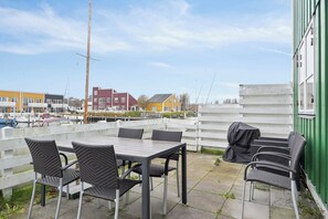 An outdoor patio with a table and chairs, a white fence, and buildings in the background.