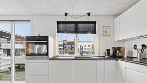 Une cuisine moderne dotée d’un four encastré, d’une fenêtre donnant sur des immeubles et d’un évier.