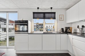 Een moderne keuken met een inbouwoven, een raam met uitzicht op gebouwen, en een spoelbak.