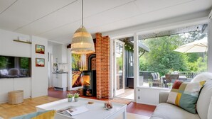 A modern living room with a fireplace, a sofa, a coffee table, and a television. - Cozy cottage near the beautiful Rågeleje beach. (Vejby)