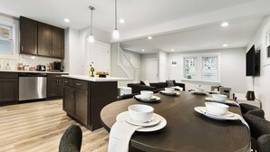 Une cuisine moderne avec des meubles de couleur sombre, un lave-vaisselle en acier inoxydable et un grand îlot central doté de bols et d’assiettes blancs.