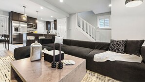 Un salon moderne avec un canapé d’angle, une table basse et une cuisine en arrière-plan.