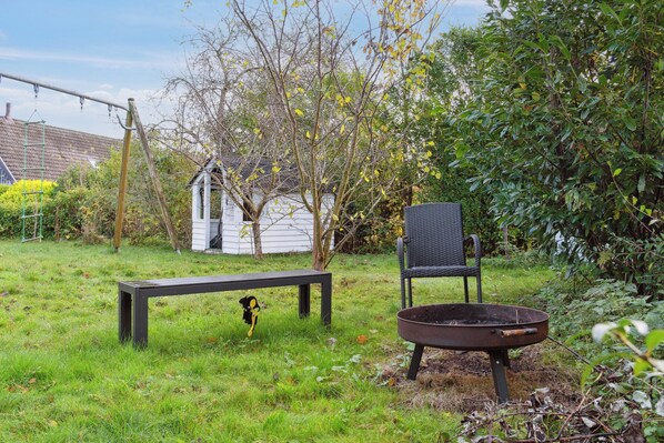 Un jardin avec un banc, une chaise et une brouette.