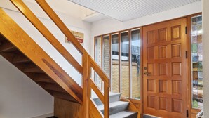 A wooden staircase leading to a landing with a door. - Large summer house in Bandholm on Lolland (Bandholm)