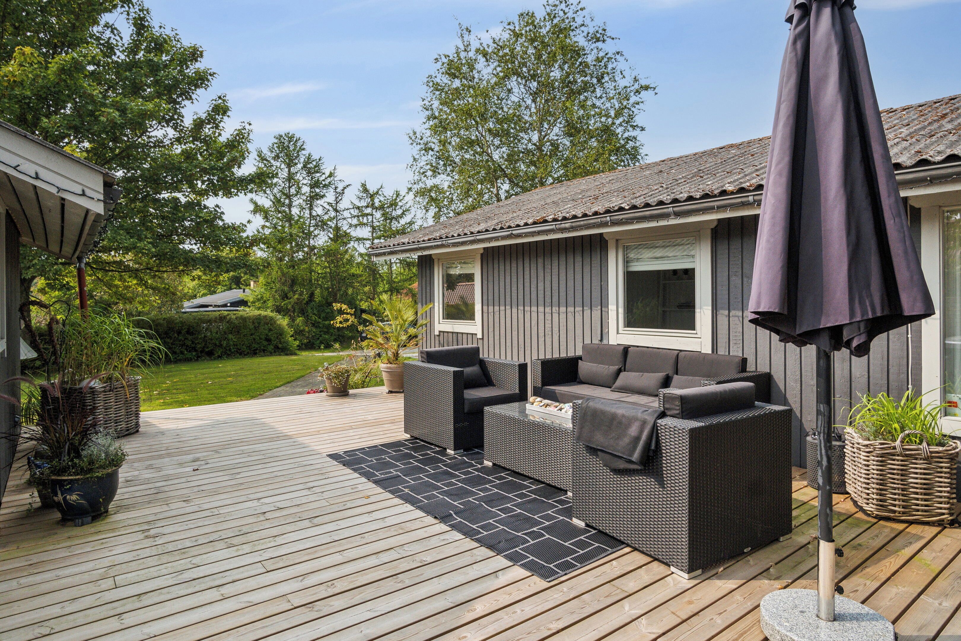 A deck with outdoor furniture, a pergola, and potted plants.
