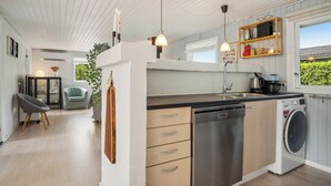 Una cocina moderna con lavavajillas, lavadora, luces colgantes y vistas al exterior.