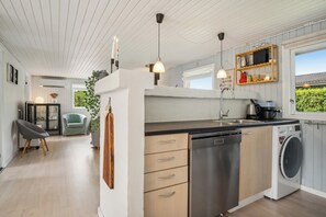 A modern kitchen with a dishwasher, a washing machine, pendant lights, and a view of the outdoors. - Lovely cottage in Pøt Strandby (Juelsminde)