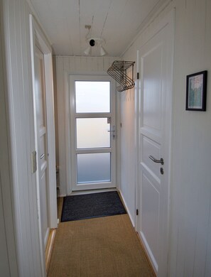 A hallway with white doors, a black doormat, and a ceiling light fixture.