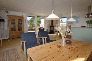 A dining area with a wooden table, blue chairs, and hanging pendant lights.