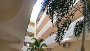 A corridor with a tiled floor, a central pathway with pebbles, and a row of palm trees. - Hotel El Imperio Punta Cana (Punta Cana)