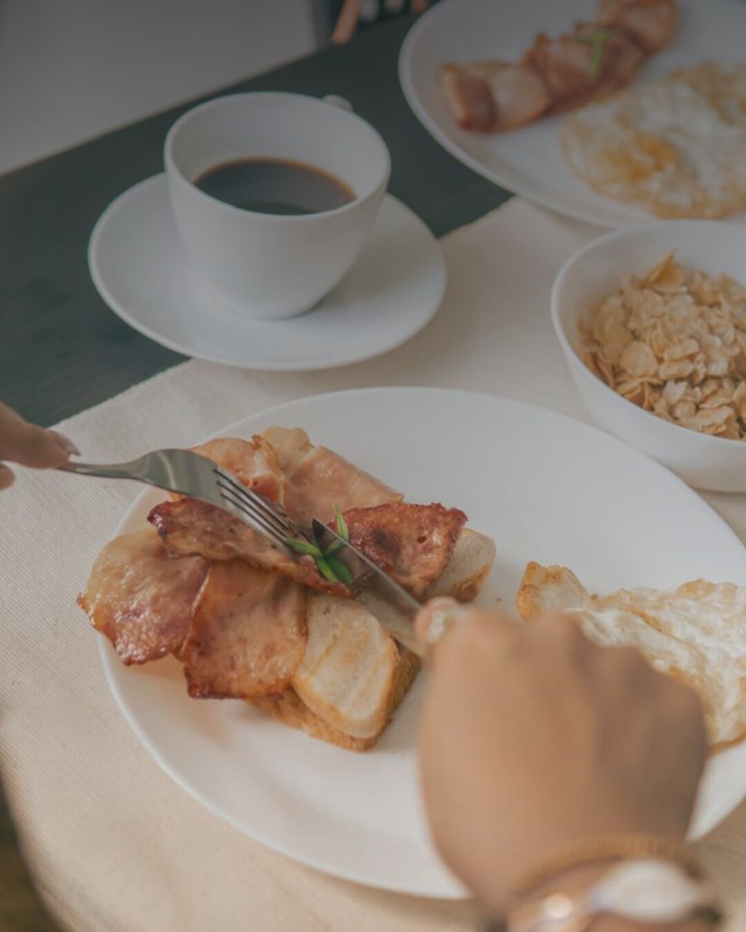 A breakfast setting with a plate of food, a cup of coffee, and a bowl of oats.