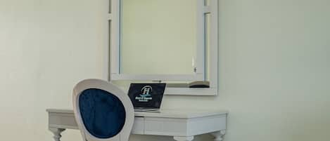 Un bureau blanc sur lequel se trouve un ordinateur portable affichant l’inscription « Hôtel Imperial Punta Cana », ainsi qu’une chaise dotée d’un coussin foncé.