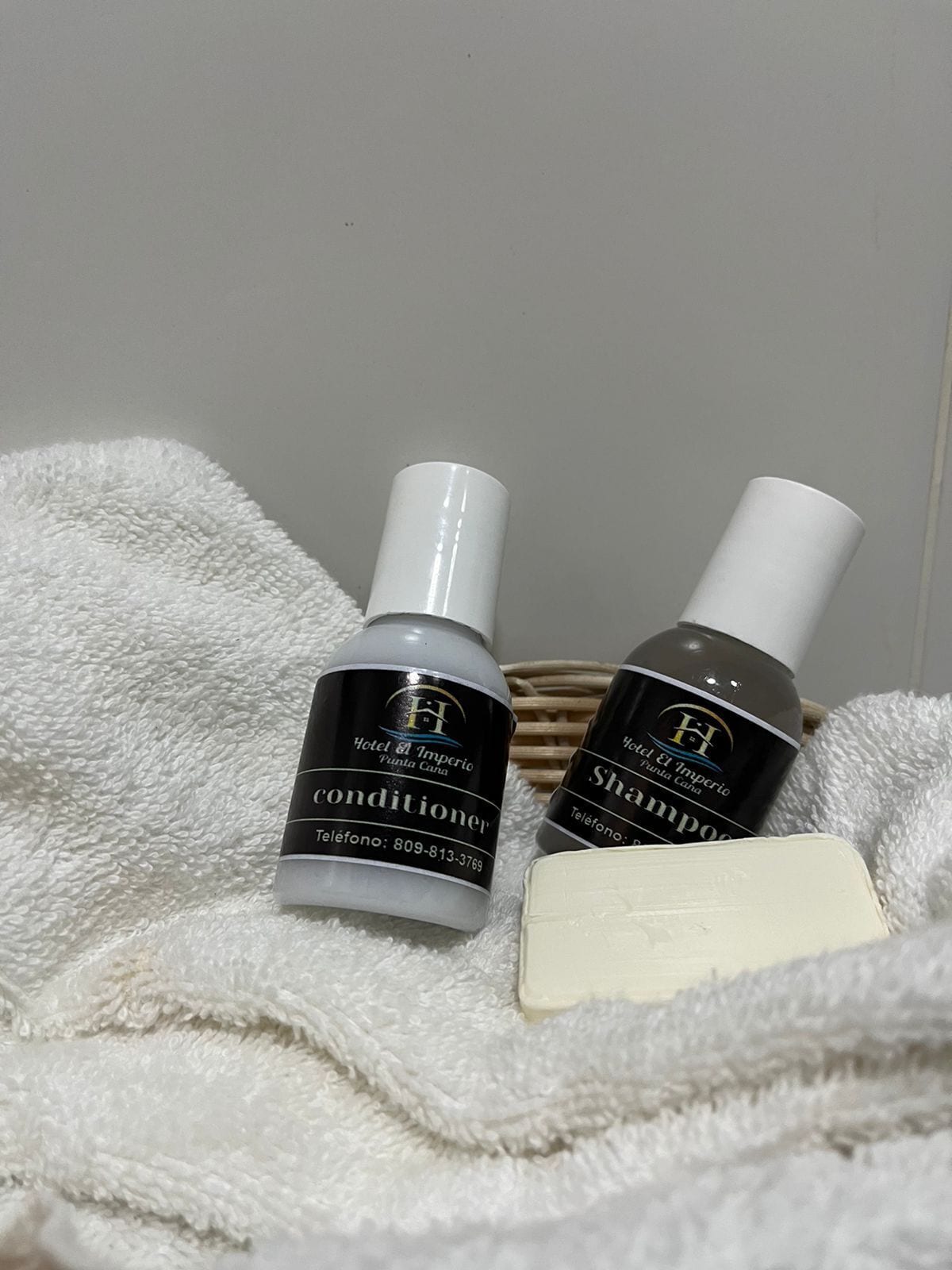 Two bottles of Hotel El Imperio products, a conditioner and shampoo, on a white towel.