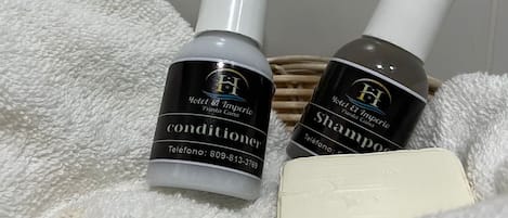 Two bottles of Hotel El Imperio products, a conditioner and shampoo, on a white towel.