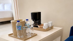 A hotel room with a bed, a coffee maker, water bottles, glasses, and a tray with cups. - Hotel El Imperio Punta Cana (Punta Cana)