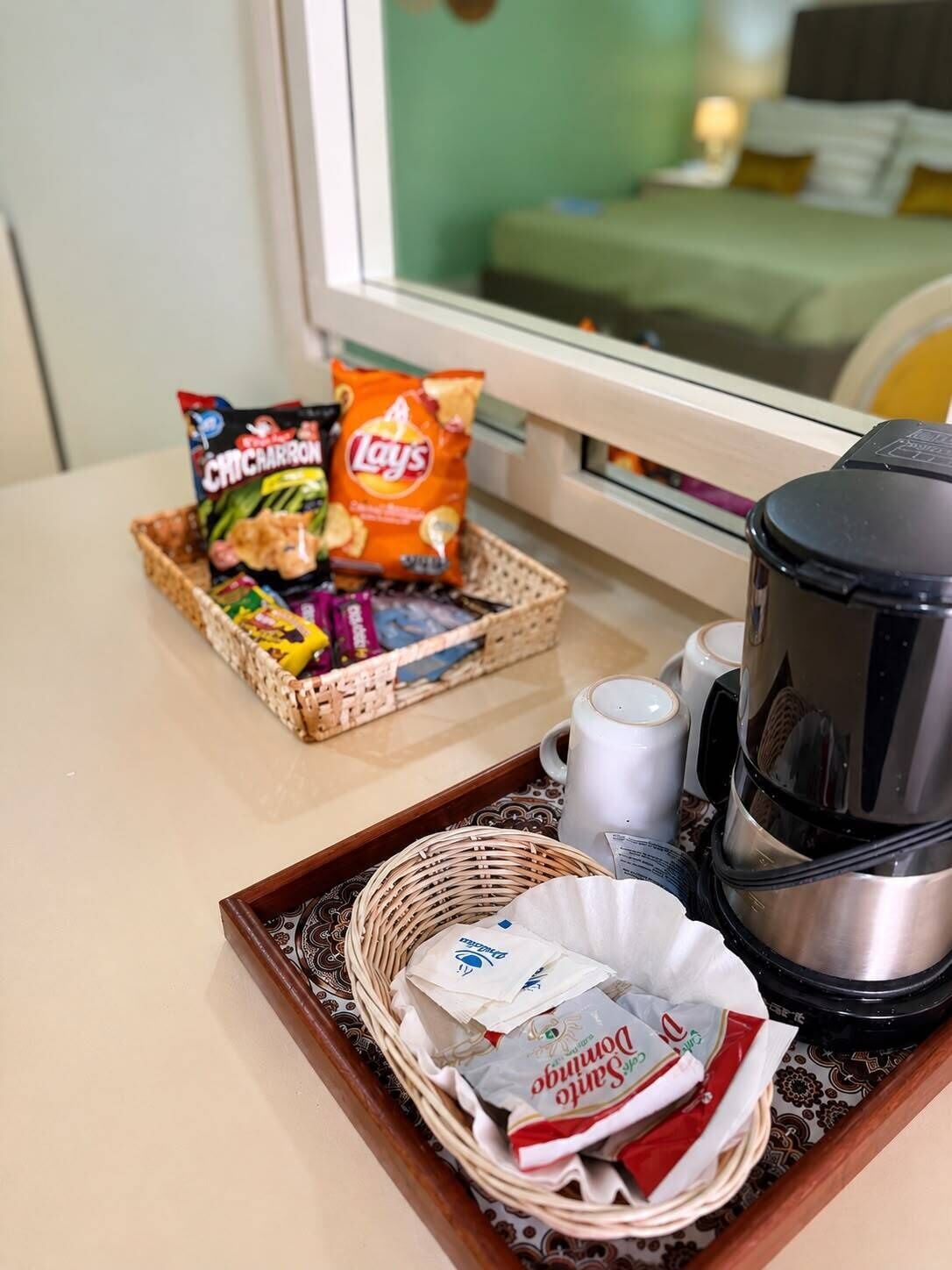 Una bandeja con aperitivos, una cafetera y una cesta de artículos de aseo.