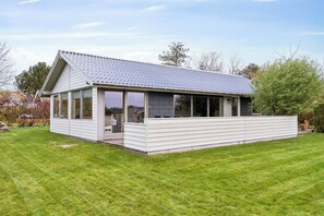 Une maison moderne avec un toit en pente, de grandes fenêtres et un patio couvert.