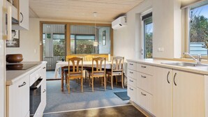 Een moderne keuken met houten kastjes, een eettafel, stoelen en een groot raam.