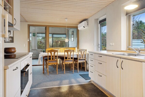 Eine moderne Küche mit Holzschränken, einem Esstisch, Stühlen und einem großen Fenster.