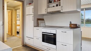 Een moderne keuken met witte kasten, een Bosch oven en een raam met uitzicht op de omgeving.