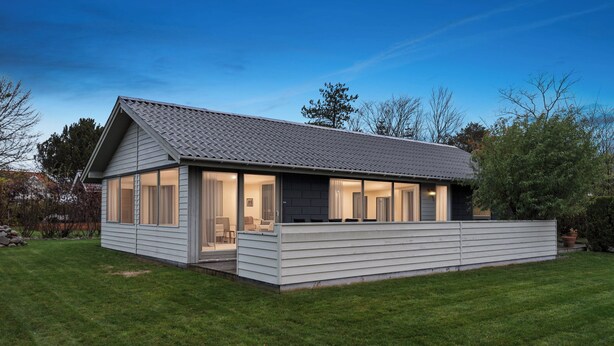 Een modern huis met een schuin dak, grote ramen en een overdekte veranda.