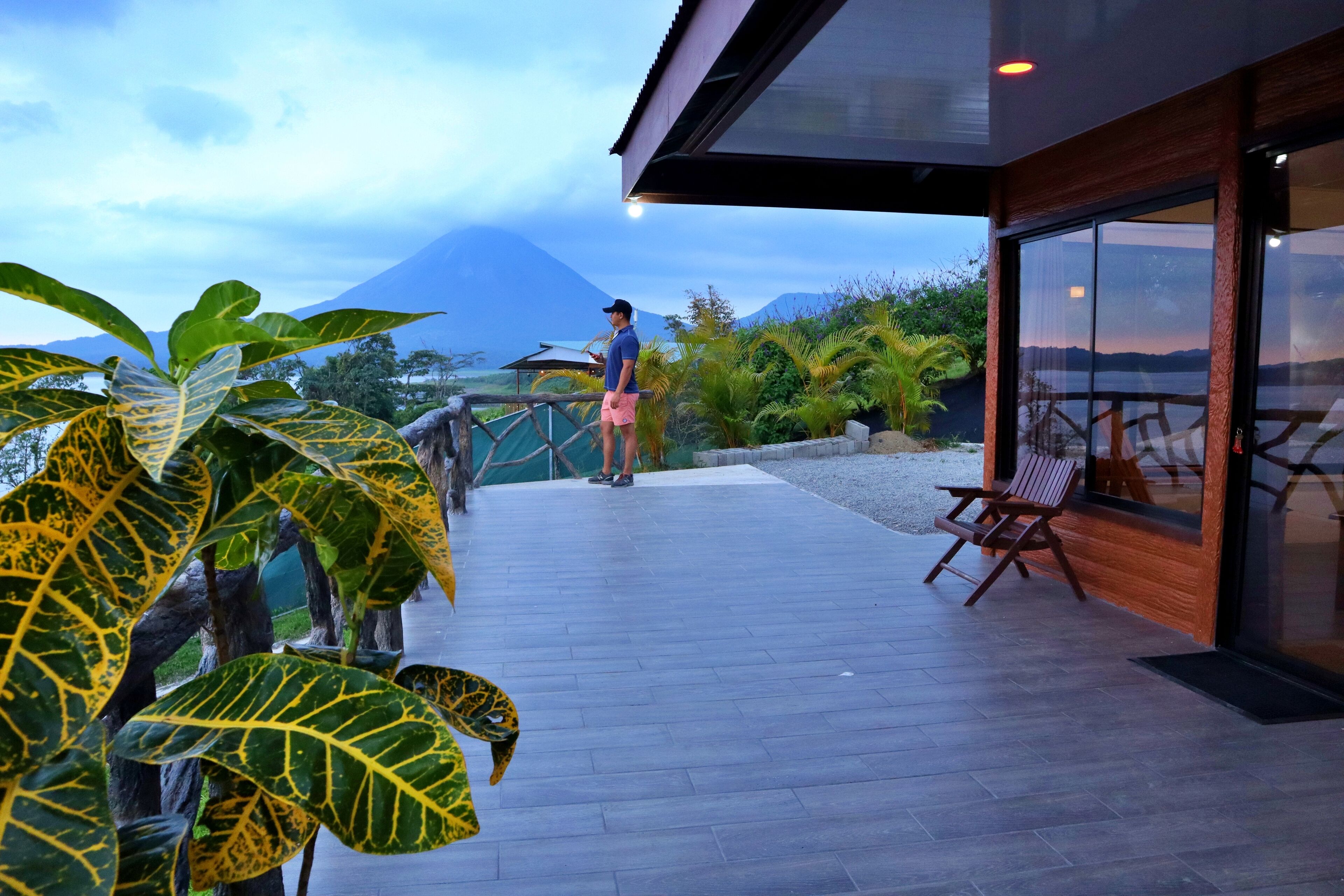 Un bâtiment moderne doté d’une terrasse en bois et de portes vitrées, offrant une vue sur un paysage montagneux.