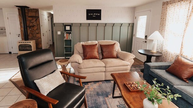 A living room with a fireplace, a sofa, a chair, a small table, and a bookshelf. - Charming Mountainview Home (Salmon)