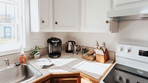 A modern kitchen with white cabinets, a coffee maker, a kettle, a sink, and a stove. - Charming Mountainview Home (Salmon)