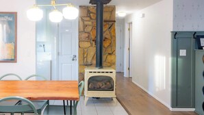 A room with a stone fireplace, a wooden dining table, and chairs. - Charming Mountainview Home (Salmon)
