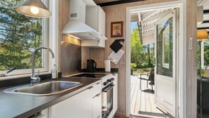 A modern kitchen with a sink, stove, and wooden cabinets. - Lovely family cottage near child-friendly beach (Aakirkeby)