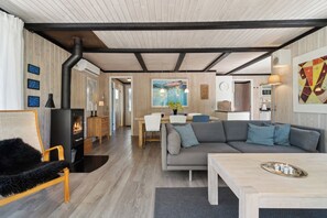 A modern living room with a fireplace, a sofa, a dining area, and a kitchen.