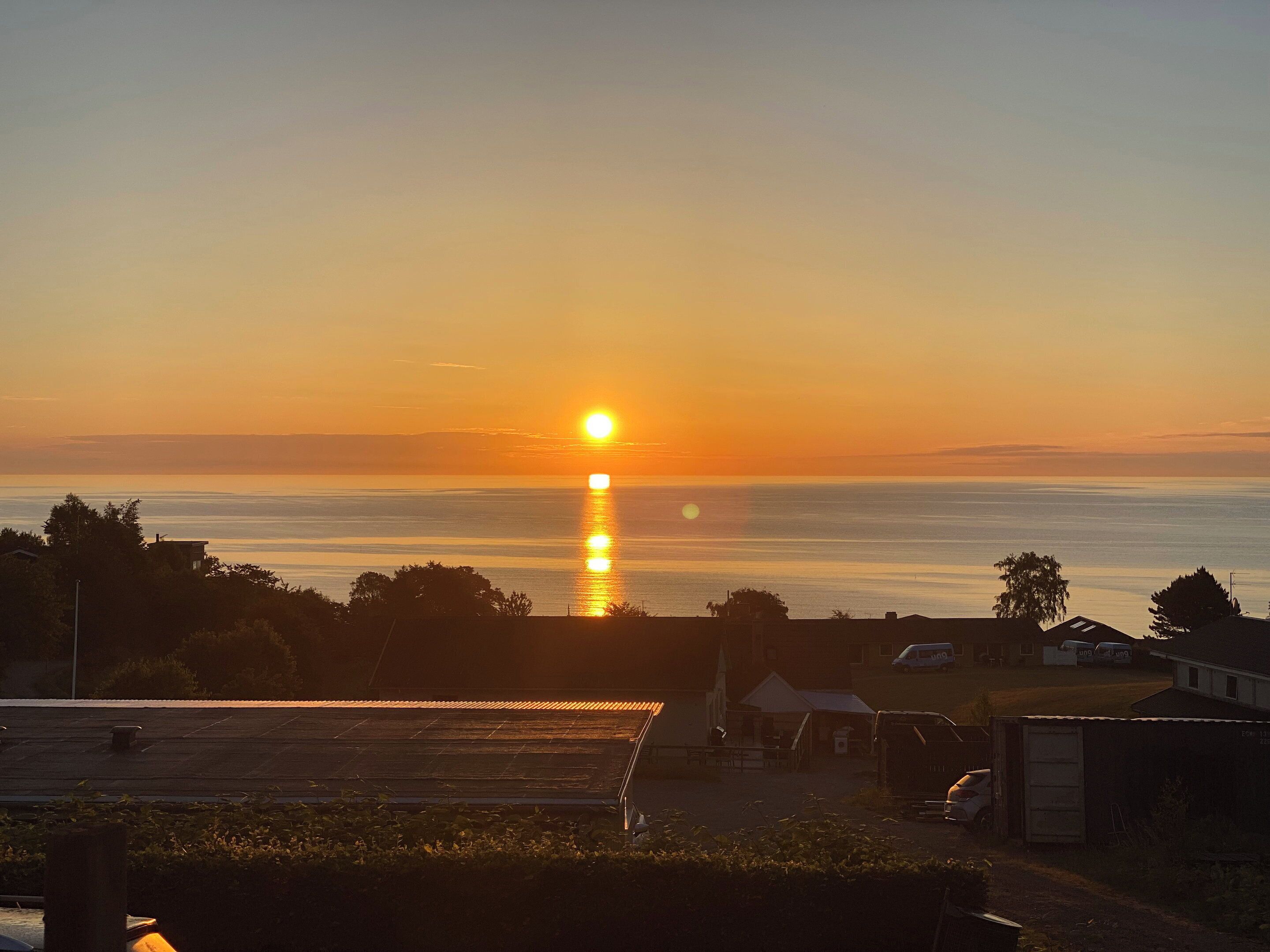 Um pôr do sol sobre a água, com edifícios ao primeiro plano.