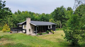 Une maison avec une cheminée, une véranda et une pelouse.