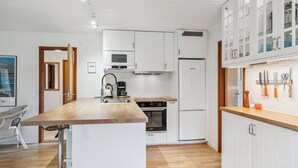Eine moderne Küche mit weißen Schränken, einer Kochinsel mit Holzplatte und einem eingebauten Backofen.