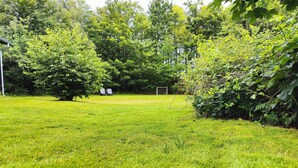 A grassy outdoor area with trees and a goalpost. - Cozy cottage steps from Lyngsbæk beach (Ebeltoft)