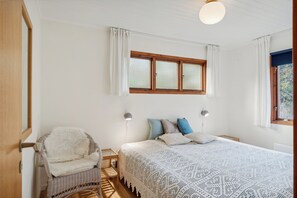 Une chambre à coucher avec un lit, une chaise, une fenêtre et une lampe.