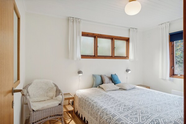 A bedroom with a bed, a chair, a window, and a lamp.