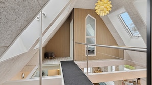 Ein modernes Interieur mit Treppe, Oberlicht und Wandverkleidung aus Holz.
