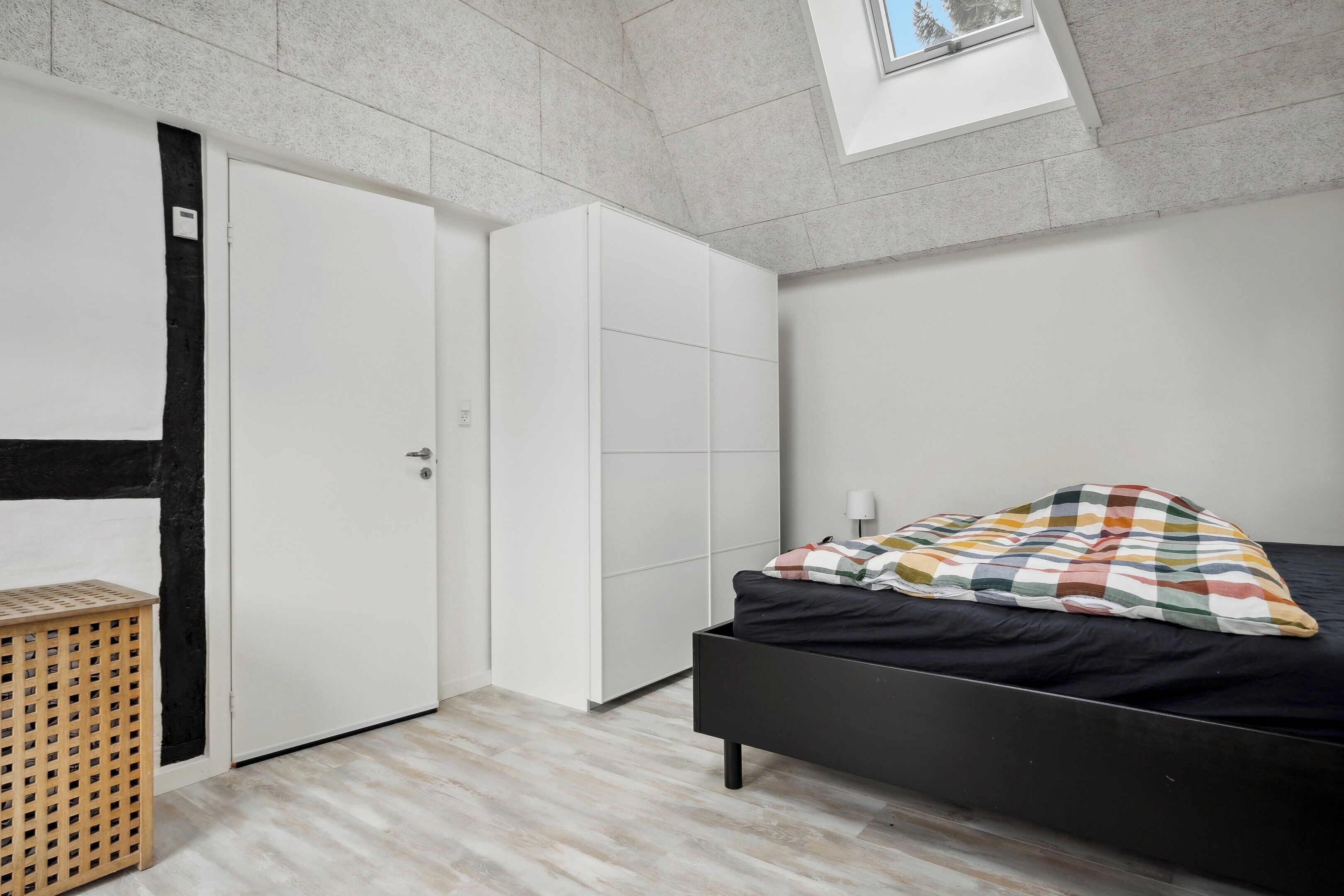 Een slaapkamer met een bed, een kledingkast en een klein houten krukje.