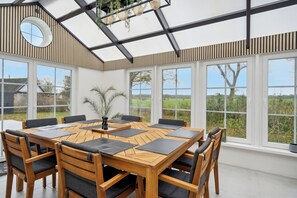 Un comedor moderno con una mesa y sillas de madera, ventanas grandes y vistas al exterior.