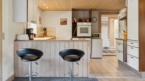 Eine moderne Küche mit Holzausstattung, einer zentralen Kochinsel mit Hockern, einer Mikrowelle und einem Kühlschrank.