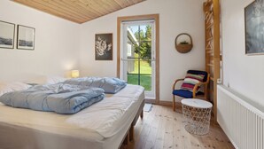 Ein Schlafzimmer mit Bett, Stuhl, rundem Tisch, Fenster und Heizkörper.