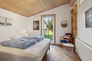 Ein Schlafzimmer mit Bett, Stuhl, rundem Tisch, Fenster und Heizkörper.