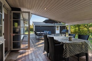 An outdoor patio with a table and chairs, a covered area, and a view of a building in the background.