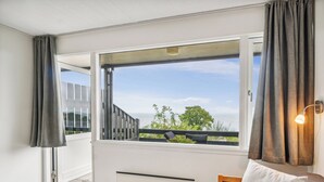 Una habitación con un ventanal grande, un radiador, un sofá y una mesita.